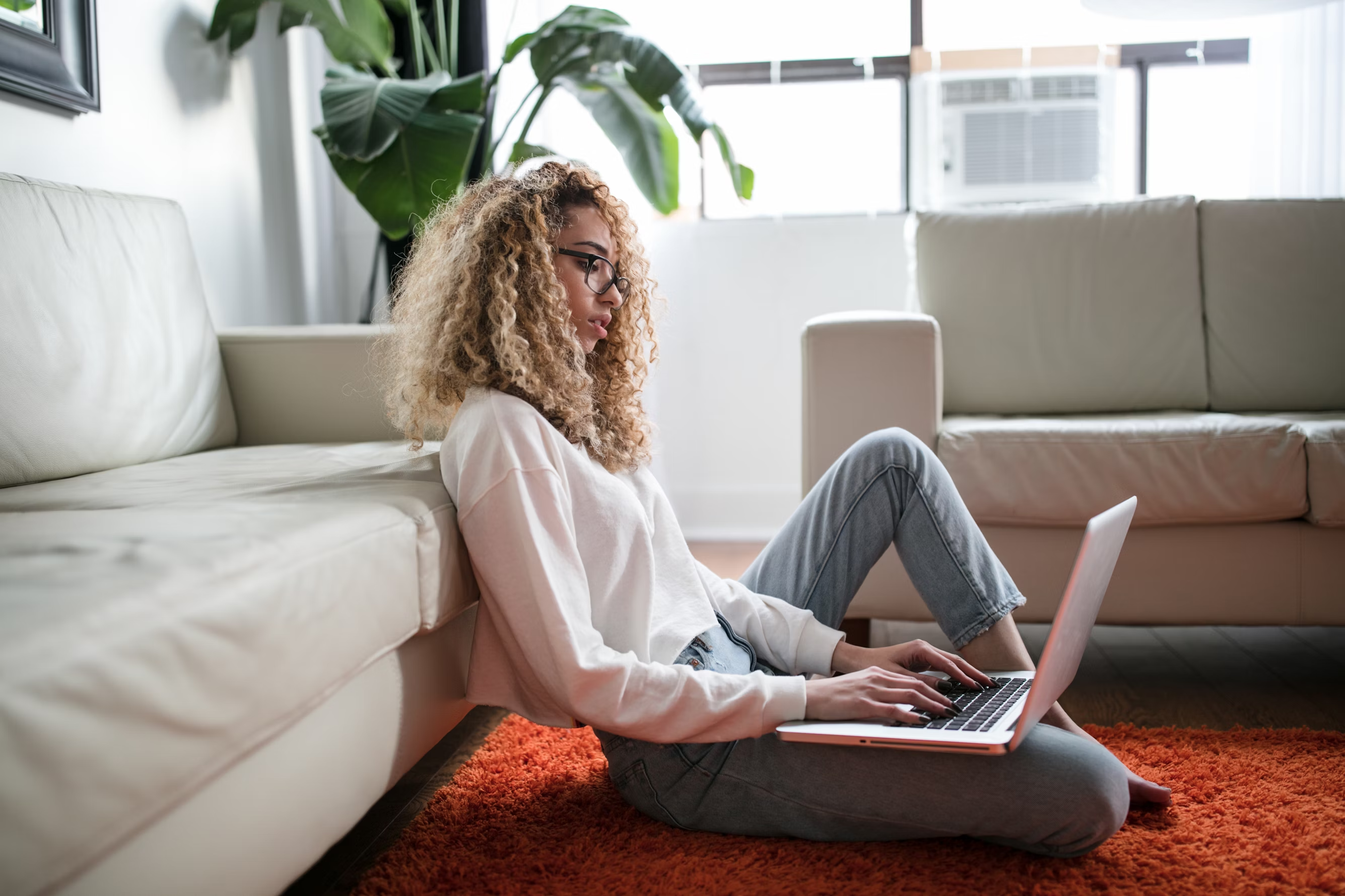 Person sitting on floor working on laptop